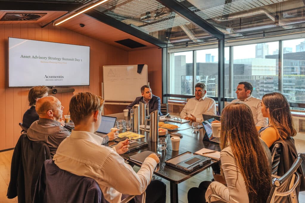 Team of professionals in a modern conference room, slide reads 'Asset Advisory Strategy Summit Day 1' on the screen.
